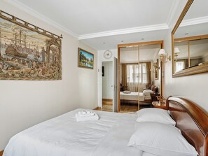 A hotel room with a large bed, a painting, a mirror, and a view into another room. - Passy - Pdt. Kennedy 2 bd by B'Your Home (Paris)