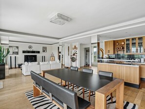 A modern living room with a dining area, kitchen, and a large window. - Passy - Pdt. Kennedy 2 bd by B'Your Home (Paris)