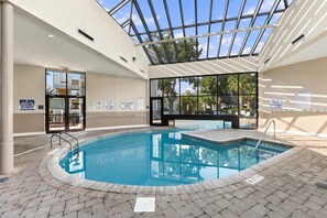An indoor swimming pool with a glass ceiling, surrounded by tiled flooring and clear signage. - Sun and Splash Myrtle Beach Resort Condo (Myrtle Beach)