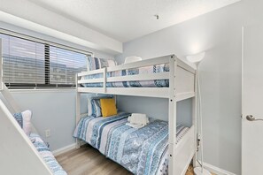 A bunk bed with patterned bedding, a window with blinds, and a door with a handle. - Sun and Splash Myrtle Beach Resort Condo (Myrtle Beach)