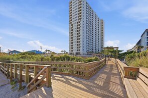 A wooden boardwalk leading to a high-rise building with multiple balconies. - Sun and Splash Myrtle Beach Resort Condo (Myrtle Beach)