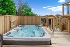 A hot tub on a wooden deck with a wooden fence and a wooden pergola in the background. - Blue Rocks Ocean Bliss for 10 (South Shore NS)