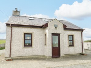 A small, single-story building with a pitched roof, a central door, and two windows on the side. - Getws (Ty Croes)