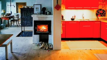Una sala de estar moderna con chimenea, un comedor y una cocina con armarios rojos.