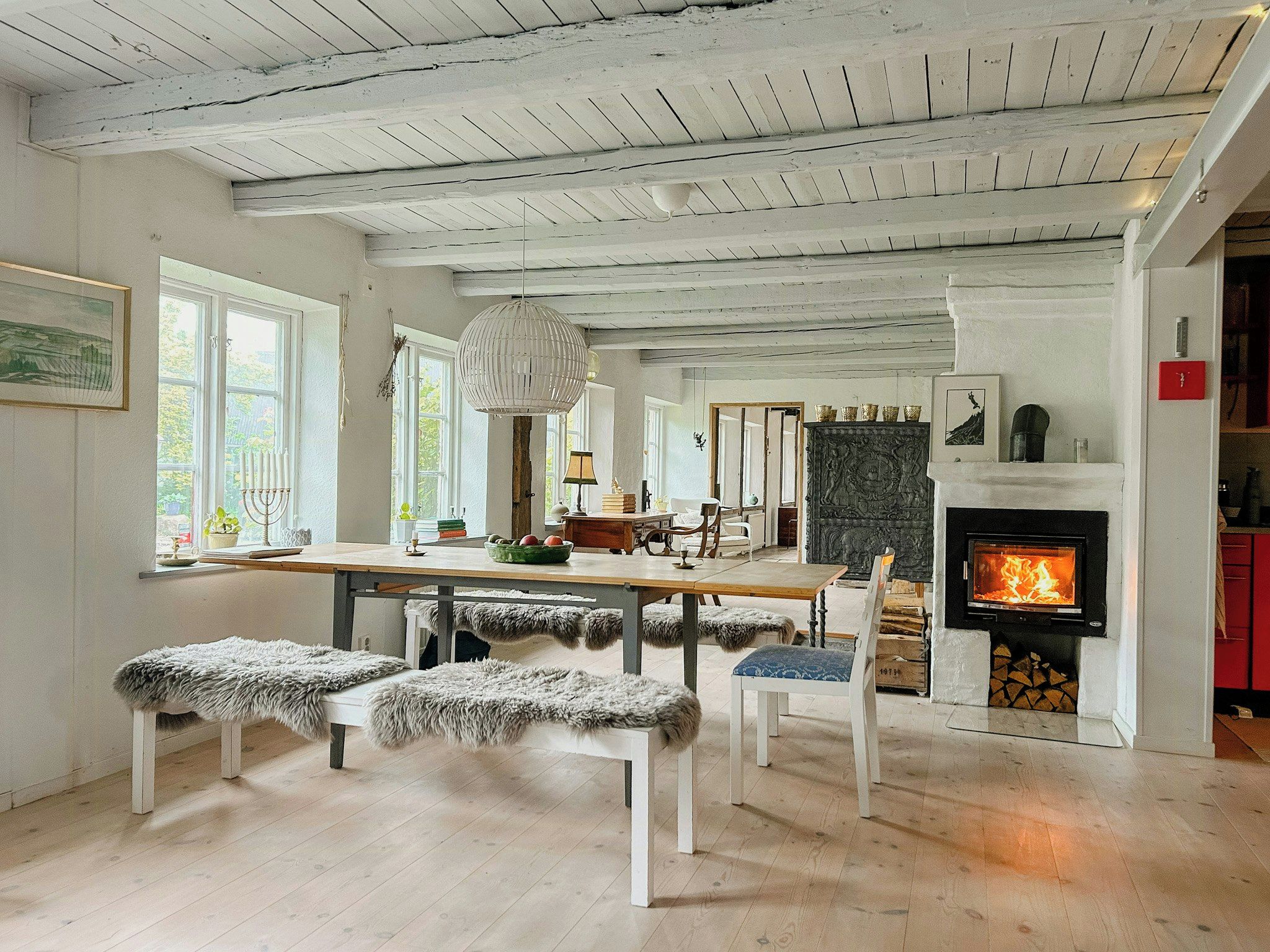 A spacious living area with a fireplace, wooden flooring, and a dining table.