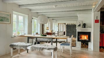 A spacious living area with a fireplace, wooden flooring, and a dining table.