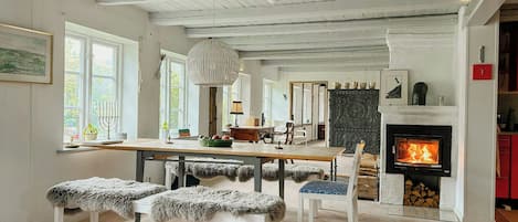 A spacious living area with a fireplace, wooden flooring, and a dining table.