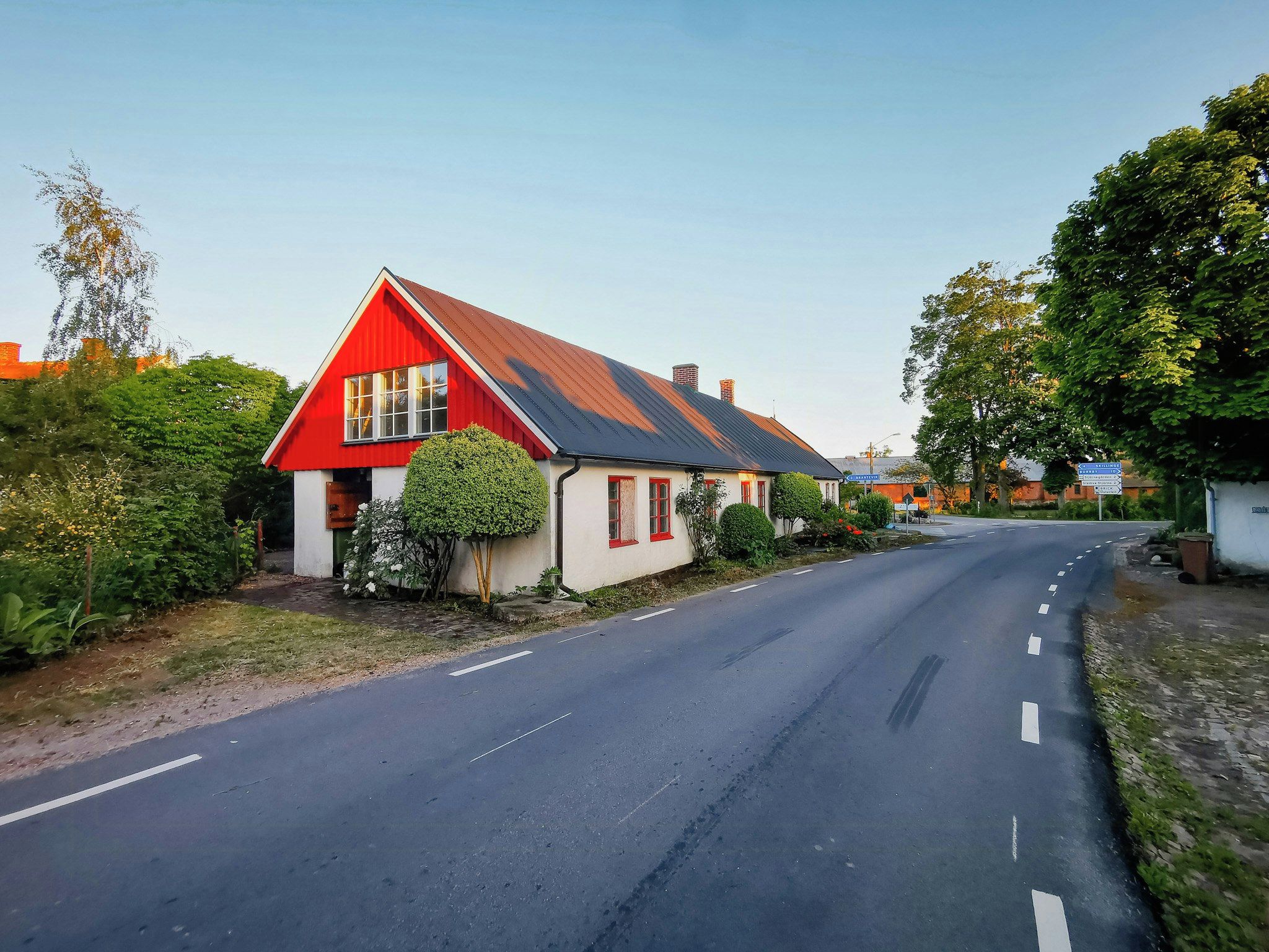 A rural road with a red house on the left.
