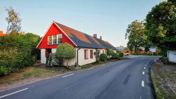 A rural road with a red house on the left.