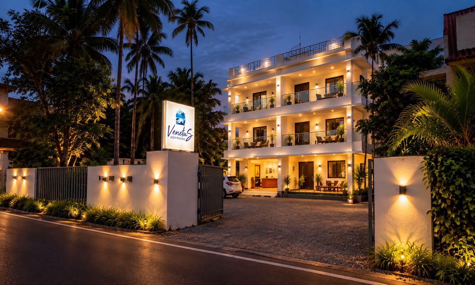 Un hotel de varios pisos con área de recepción, asientos al aire libre y una entrada bien iluminada.