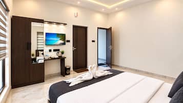 Una habitación de hotel con cama, escritorio, televisor, armario y puerta.