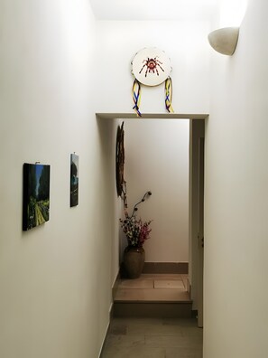 A hallway with a door leading to another room, a wall-mounted light fixture, and two paintings. - Villa 'Mios' with Private Terrace, Wi-Fi and Air Conditioning (Muro Leccese)
