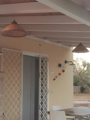 An outdoor patio area with a table and chairs, a decorative wall with heart-shaped ornaments, and a hanging light fixture. - Villa 'Mios' with Private Terrace, Wi-Fi and Air Conditioning (Muro Leccese)