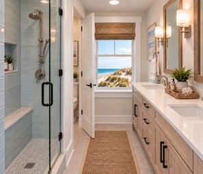 A bathroom with a shower, a toilet, a sink, and a window with a view of the beach. - Direct Oceanfront-New Construction for 2027 (Kitty Hawk)