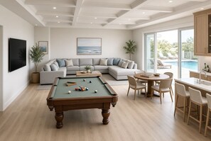 A modern living room with a pool table, a sectional sofa, and a dining area with a view of the pool. - Direct Oceanfront-New Construction for 2027 (Kitty Hawk)