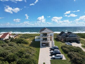 A coastal property with a two-story building, a parking area, and a view of the ocean. - Direct Oceanfront-New Construction for 2027 (Kitty Hawk)