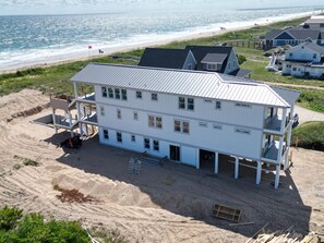 Un edificio de varios pisos con techo plano, cerca de una playa y vista al océano.