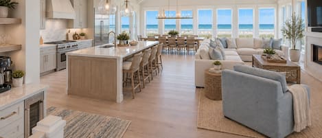 A spacious living area with a large window overlooking the beach, a kitchen with modern appliances, and a cozy seating area with a fireplace.