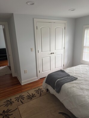 Ein Schlafzimmer mit einem Bett, einer weißen Tür und einem Fenster mit Jalousien.