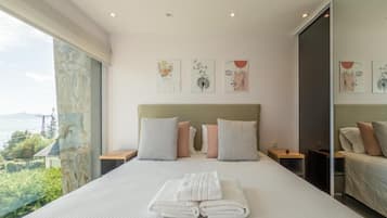 A hotel room with a large bed, a view of the outdoors, and artwork on the walls.