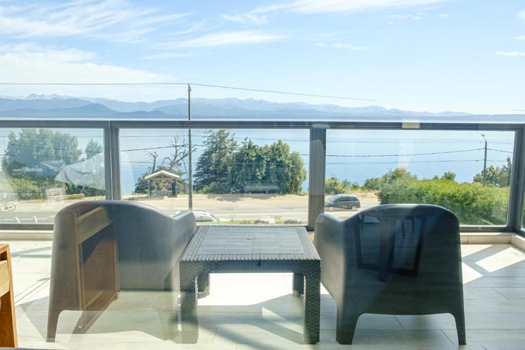 Ein Balkon mit Blick auf einen See und Berge, ausgestattet mit einem Tisch und Stühlen.
