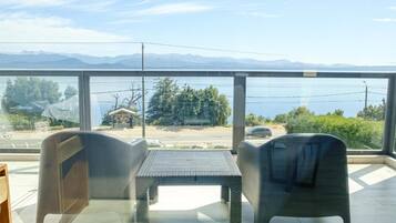 Ein Balkon mit Blick auf einen See und Berge, ausgestattet mit einem Tisch und Stühlen.