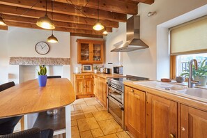 A kitchen with wooden cabinets, a stove, a sink, and pendant lighting. - Host Stay - West Loanend Cottage (Berwick-upon-Tweed)