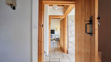 A wooden door leading to a stone-walled room with a television and a white shelf.