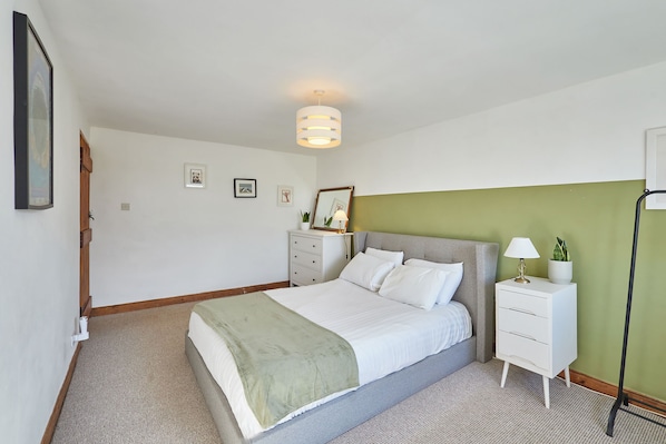 A bedroom with a bed, bedside tables, a lamp, and a wall-mounted picture frame. - Host Stay - West Loanend Cottage (Berwick-upon-Tweed)