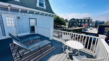 Une terrasse dotée de mobilier d’extérieur, d’une porte et offrant une vue sur les bâtiments environnants.