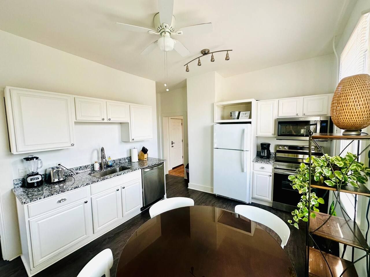 A modern kitchen with white cabinetry, a central island, and a ceiling fan.