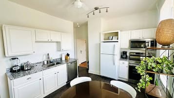 A modern kitchen with white cabinetry, a central island, and a ceiling fan.