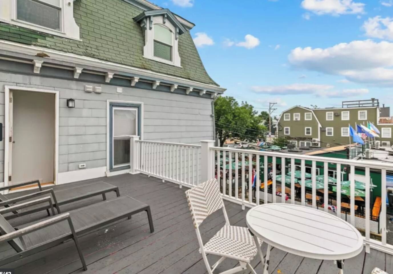 A deck with a white railing, a round table, and two chairs.