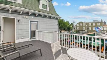 A deck with a white railing, a round table, and two chairs.