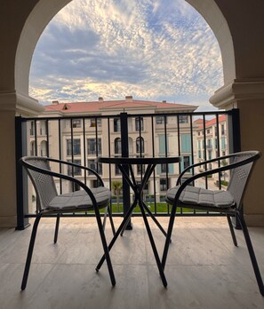 Ein Balkon mit zwei Stühlen und einem Tisch, mit Blick auf eine Häuserreihe mit roten Dächern.