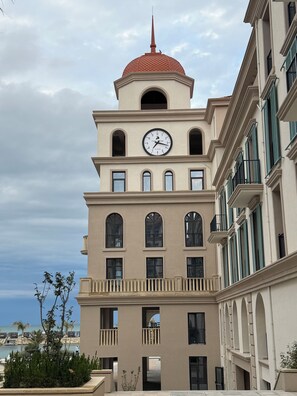 A multi-story building with a clock tower, balconies, and a view of the sea. - Marina Village: luxury 1-bedroom apartment by seaside in Nardaran, Baku (Nardaran)