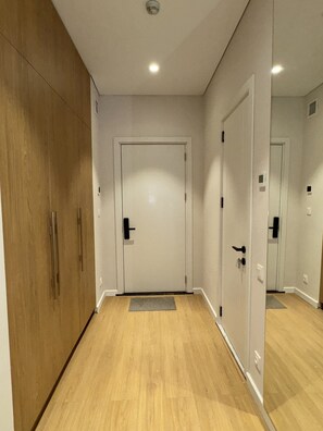 Ein Flur mit einem Holzschrank, einer weißen Tür und einem Spiegel, der die Tür widerspiegelt.