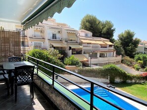 A balcony with a pool, outdoor furniture, and a view of neighboring buildings. - Apartment in Nerja Near Burriana Beach (Nerja)