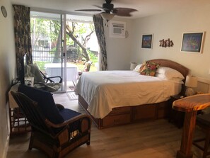 Ein Schlafzimmer mit Bett, Stuhl, Schreibtisch und einem Fenster mit Vorhängen.