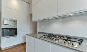 Eine moderne Küche mit Edelstahlgeräten, darunter ein Herd und ein Backofen, sowie weißen Schränken.
