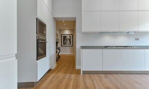 A modern kitchen with white cabinetry, a built-in oven, and a stainless steel range hood. - BRIGHT LUXURY 4-BEDROOM APARTMENT IN THE HEART OF FLORENCE (Firenze)