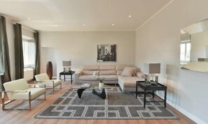 A modern living room with a sofa, chairs, a coffee table, and two side tables. - BRIGHT LUXURY 4-BEDROOM APARTMENT IN THE HEART OF FLORENCE (Firenze)