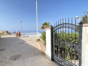 A paved walkway leading to a gate with a view of the sea. - Apartment in Nerja Near Burriana Beach (Nerja)