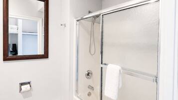 A bathroom with a glass-enclosed shower, a toilet, a towel rack, and a mirror on the wall.