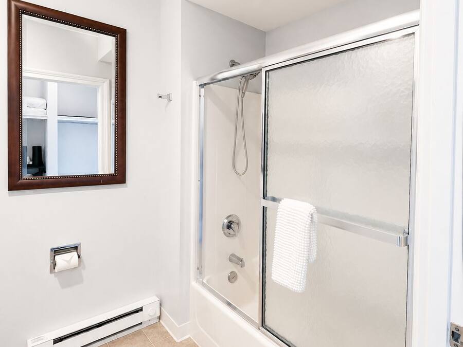 A bathroom with a glass-enclosed shower, a toilet, a towel rack, and a mirror on the wall.