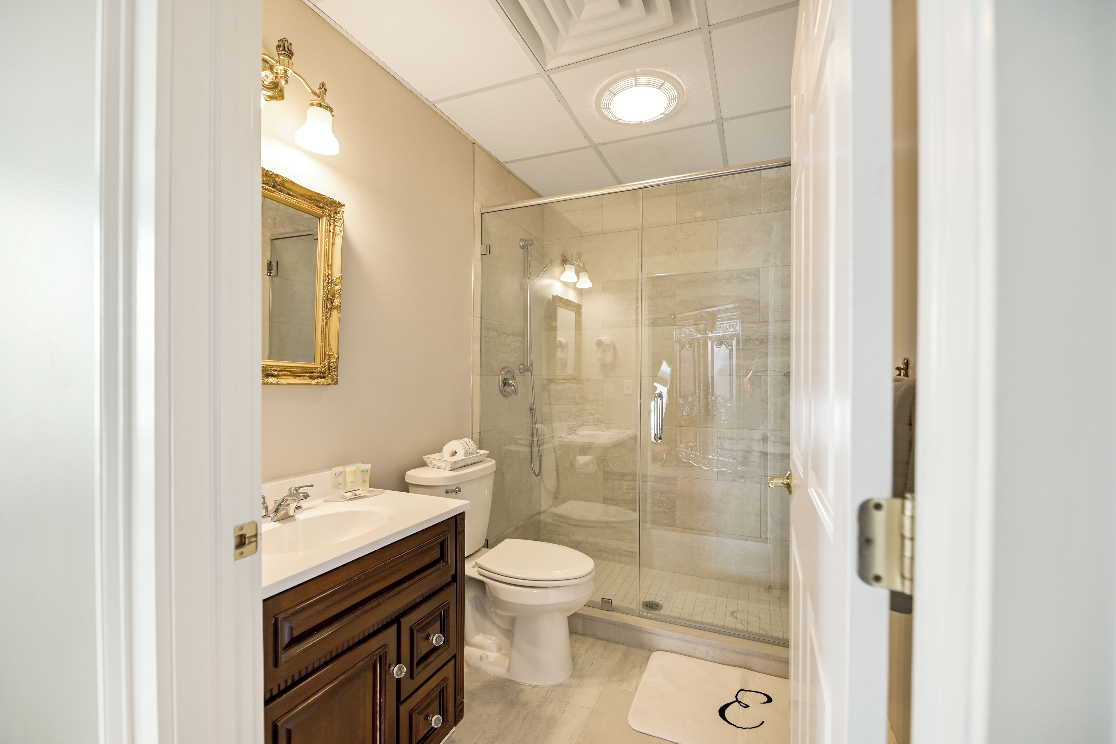 A bathroom with a glass-enclosed shower, a white toilet, and a vanity with a mirror.