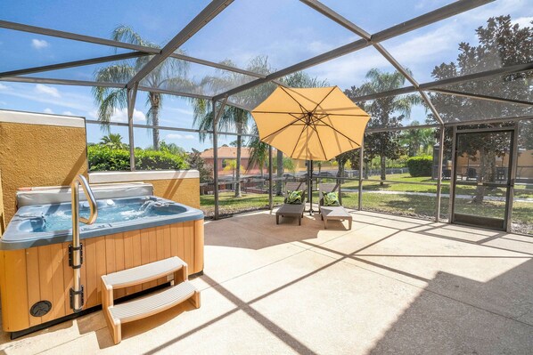 A covered outdoor area with a hot tub, seating, and an umbrella. - 3BR themed rooms near Disney | Private hot tub (Kissimmee)