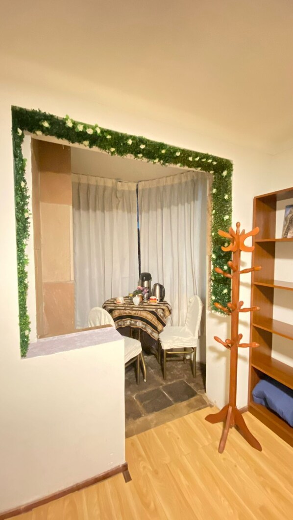 A room with a dining table, chairs, a coffee machine, and a bookshelf.