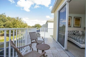 A balcony with a seating area, a sliding glass door leading to a room with a bed and a sofa. - 3BR near Disney | Mickey room, private pool (Clermont)