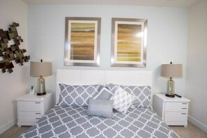 A bedroom with a bed, two bedside tables, two lamps, and two framed pictures on the wall. - 3BR near Disney | Mickey room, private pool (Clermont)